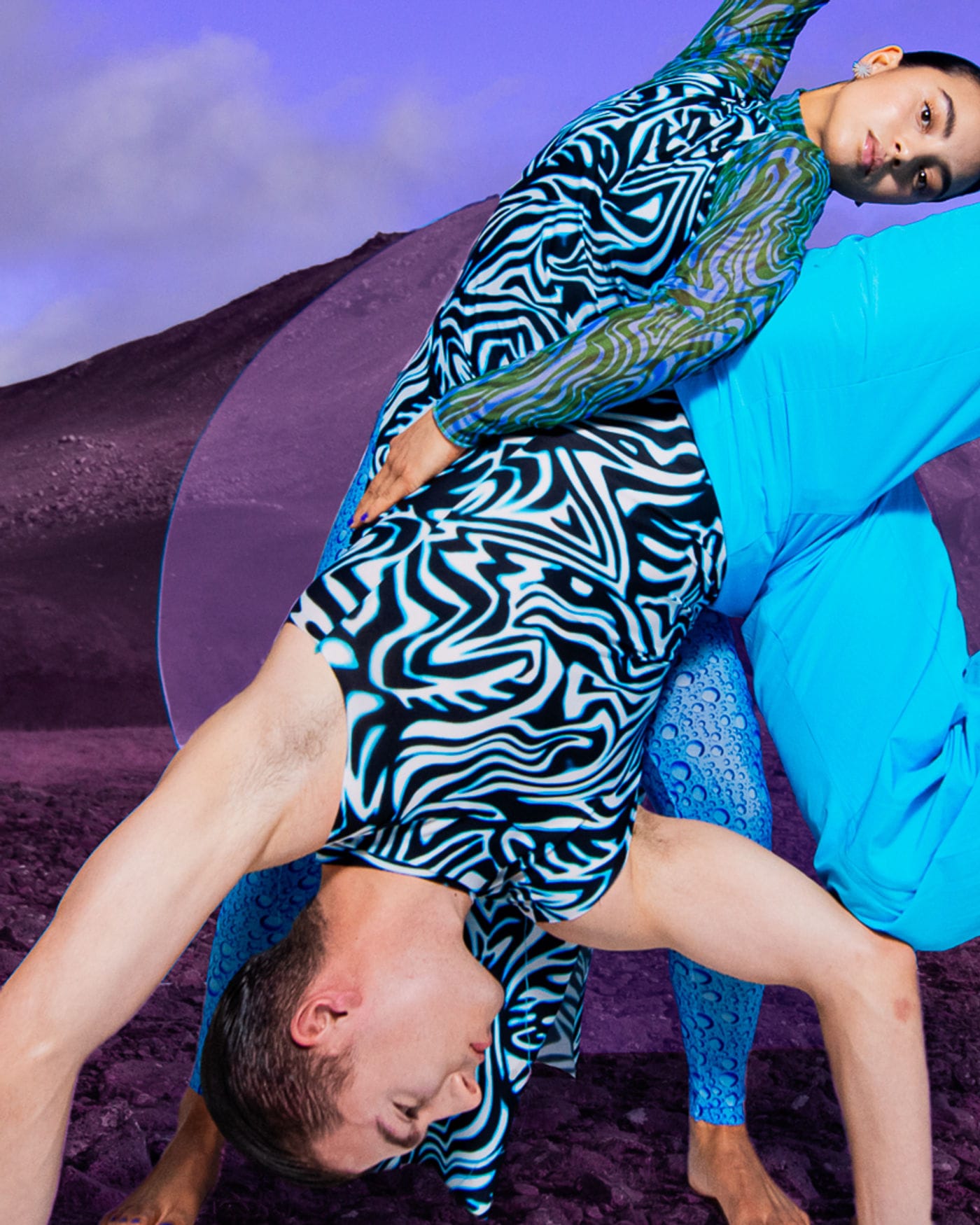Twee dansers in blauw en zebraprint tegen een paarse lucht